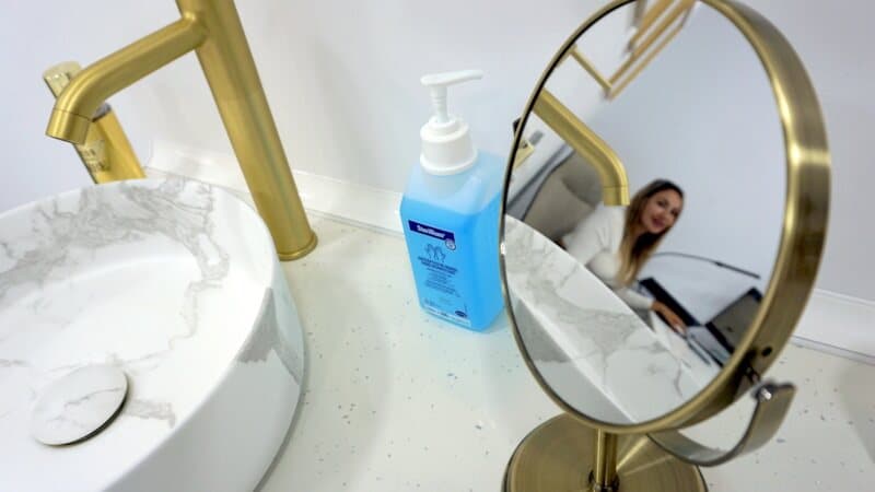 Detalle del lavabo de mármol con grifería dorada en la consulta