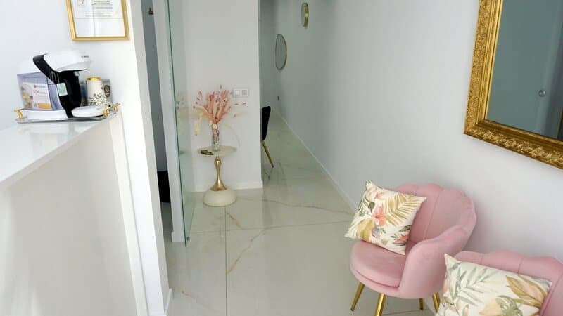 Recepción y sala de espera de la clínica, con sillones rosas y detalles dorados