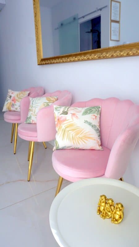 Sala de espera con sillones rosas y espejo dorado
